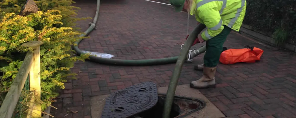Septic tank cleaning technician servicing a septic tank with a vacuum hose in Easton, PA